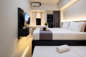 Ein modernes Hotelzimmer mit einem Bett, einem Fernseher, einem Nachttisch und einem Fenster mit Vorhängen.