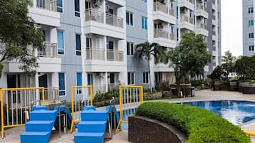 Un immeuble résidentiel à plusieurs étages doté de balcons, d’une piscine et d’équipements de fitness en plein air.
