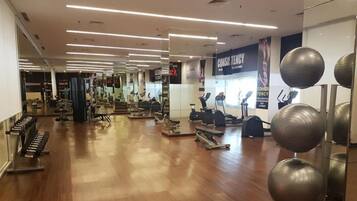 Ett gym med olika typer av träningsutrustning, inklusive löpband och styrketräningsmaskiner.