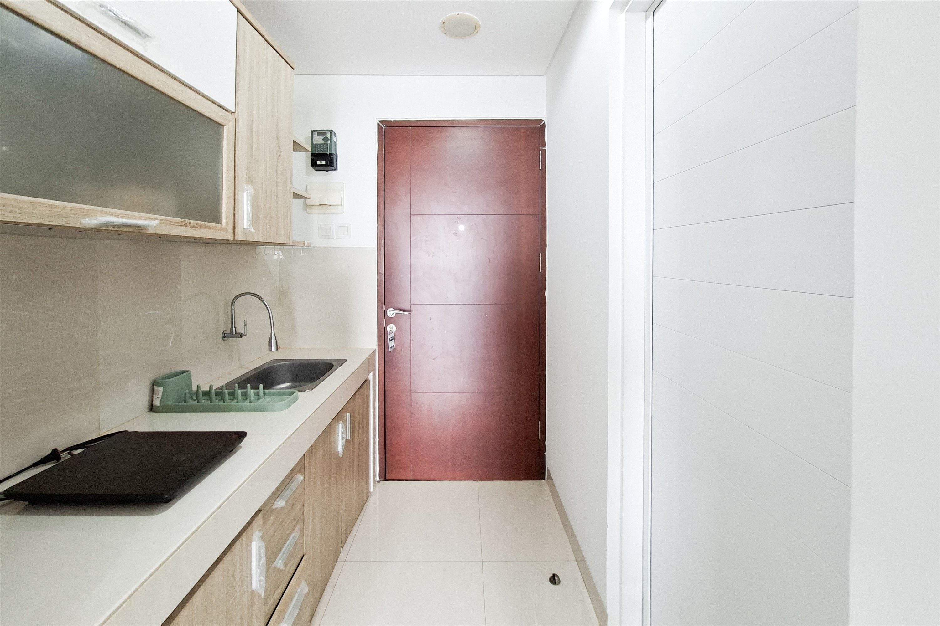Una cocina estrecha con un lavamanos, armarios y una puerta.
