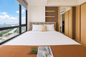 Ein Hotelzimmer mit großem Fenster, einem Bett mit weißer Bettwäsche, einer Zeitschrift auf dem Bett und Blick auf eine Stadtlandschaft.