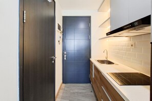 Une cuisine étroite avec une porte sombre, un évier en acier inoxydable et une hotte de cuisine moderne.
