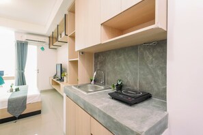 A modern kitchen with a built-in dishwasher, a sink, and a countertop with a portable appliance. - Minimalist Studio At Apartment B Residence Grogol (Jakarta)