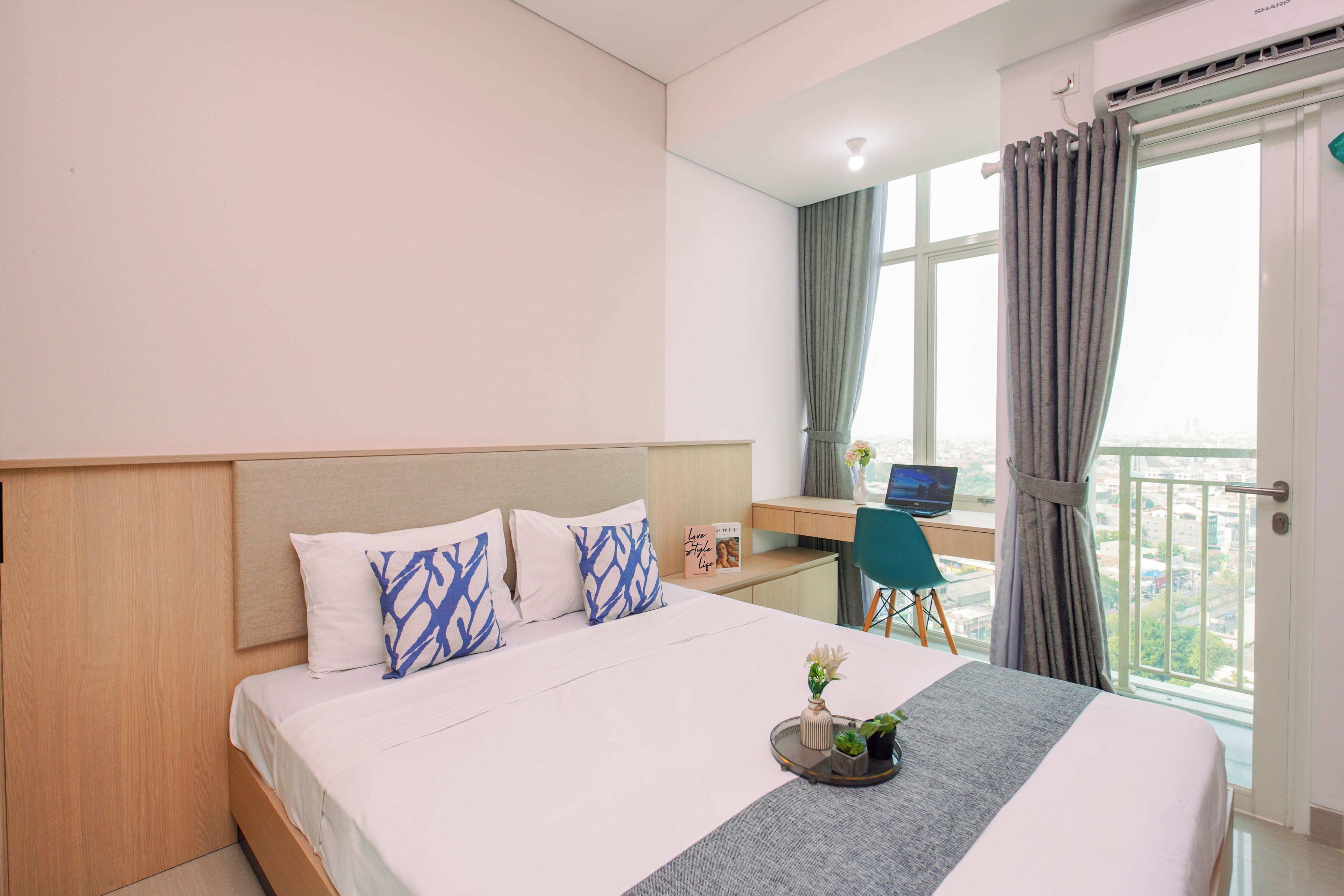 Quarto de hotel com cama, escrivaninha, laptop e vista da cidade.