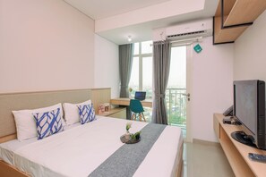 Ein Hotelzimmer mit Bett, Schreibtisch mit Computer, Fernseher und Blick auf die Stadt durch das Fenster.