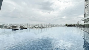 Ein Rooftop-Pool mit Infinity-Kante, Liegestühlen und Blick auf die Stadt.