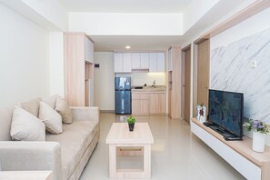 Un salon moderne avec un canapé, une table basse et un téléviseur posé sur un meuble.