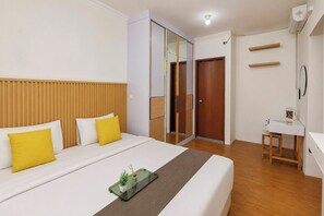 Ein Hotelzimmer mit Bett, Nachttisch, Spiegel, Kleiderschrank und kleinem Schreibtisch.