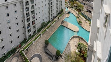 En høj bygning med swimmingpool og anlagt have.
