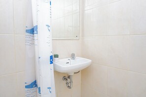 A bathroom with a white sink, a mirror above it, and a shower curtain with a wave pattern. - Functional Homey Studio Room At Apartment Springlake Summarecon Bekasi (Bekasi)