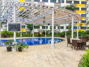 An indoor swimming pool with a covered seating area, surrounded by potted plants and outdoor furniture. - Functional Homey Studio Room At Apartment Springlake Summarecon Bekasi (Bekasi)
