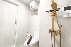 Ein Badezimmer mit Toilette, Duschkabine und weißer Wand.