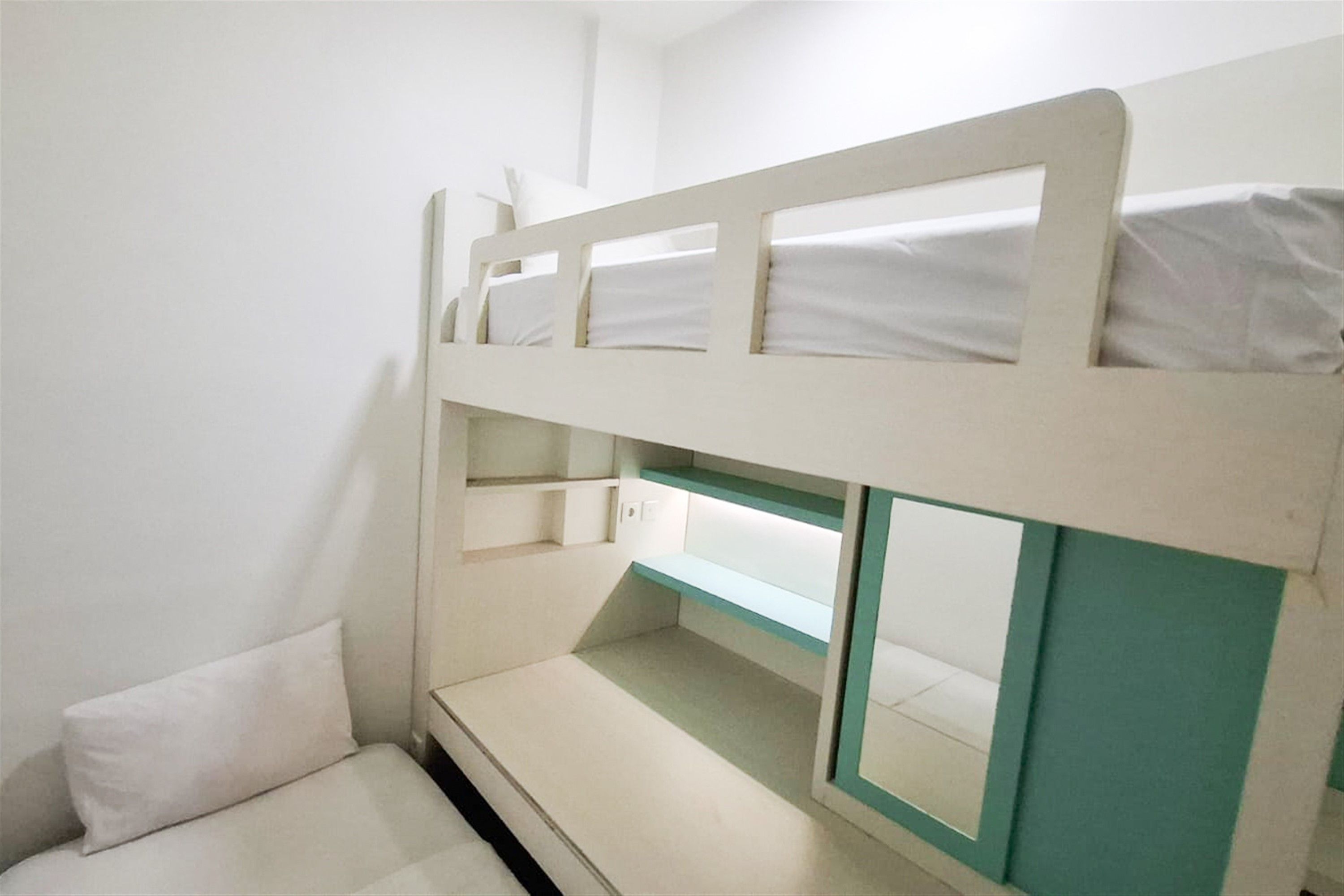 A bunk bed with a lower bunk and a small seating area below.