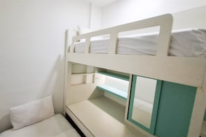 Una cama litera con una cama inferior y un pequeño rincón de descanso abajo.