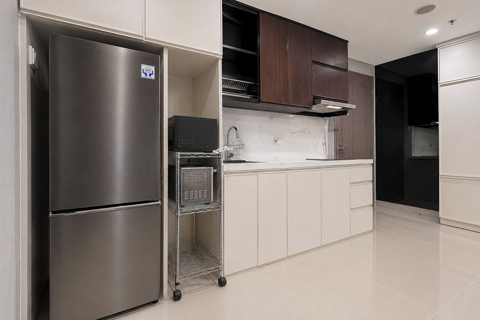 A modern kitchen with stainless steel appliances, white cabinetry, and a tiled floor.
