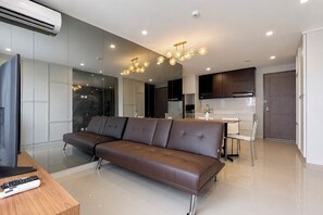 Een moderne woonkamer met een bruine leren bank, een houten salontafel en een televisie.