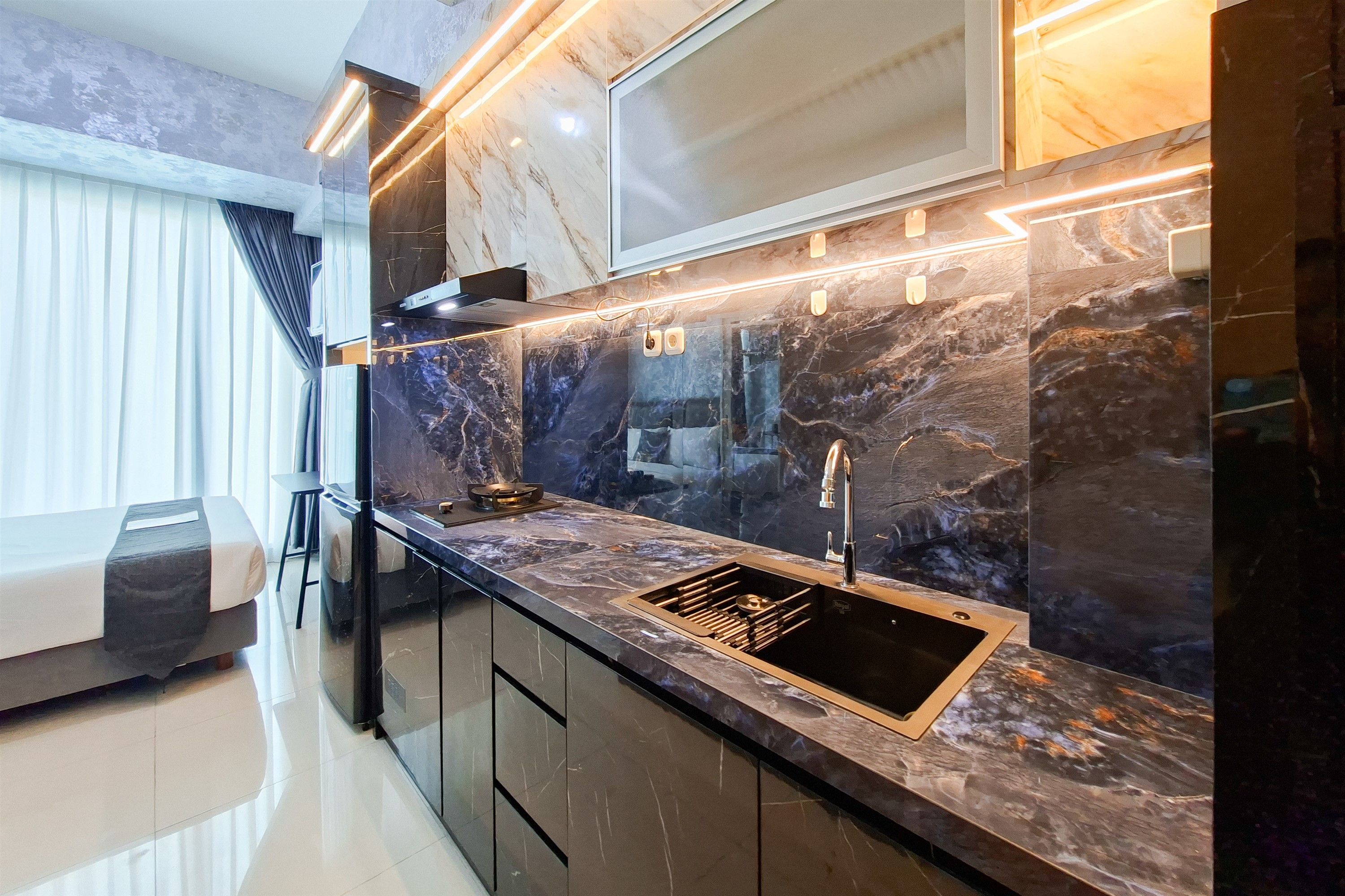 A modern kitchen with a black countertop, a stainless steel sink, and a built-in stove.