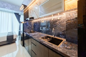 Una cocina moderna con encimera negra, pileta de acero inoxidable y cocina integrada.