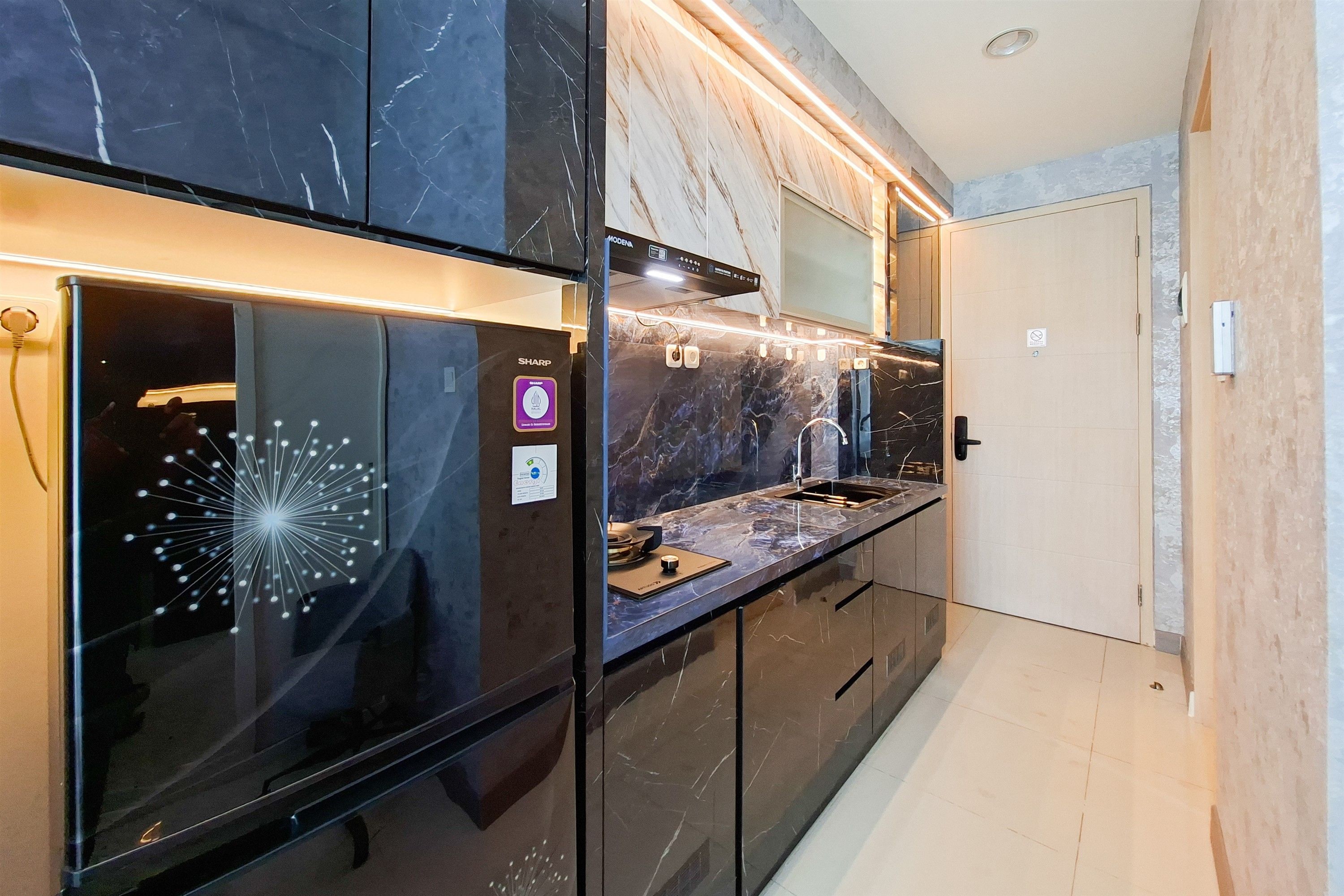 A modern kitchen with a black refrigerator, a built-in oven, and a marble backsplash.