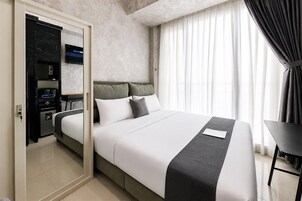 Una habitación de hotel moderna con una cama, un escritorio, un armario y un televisor.