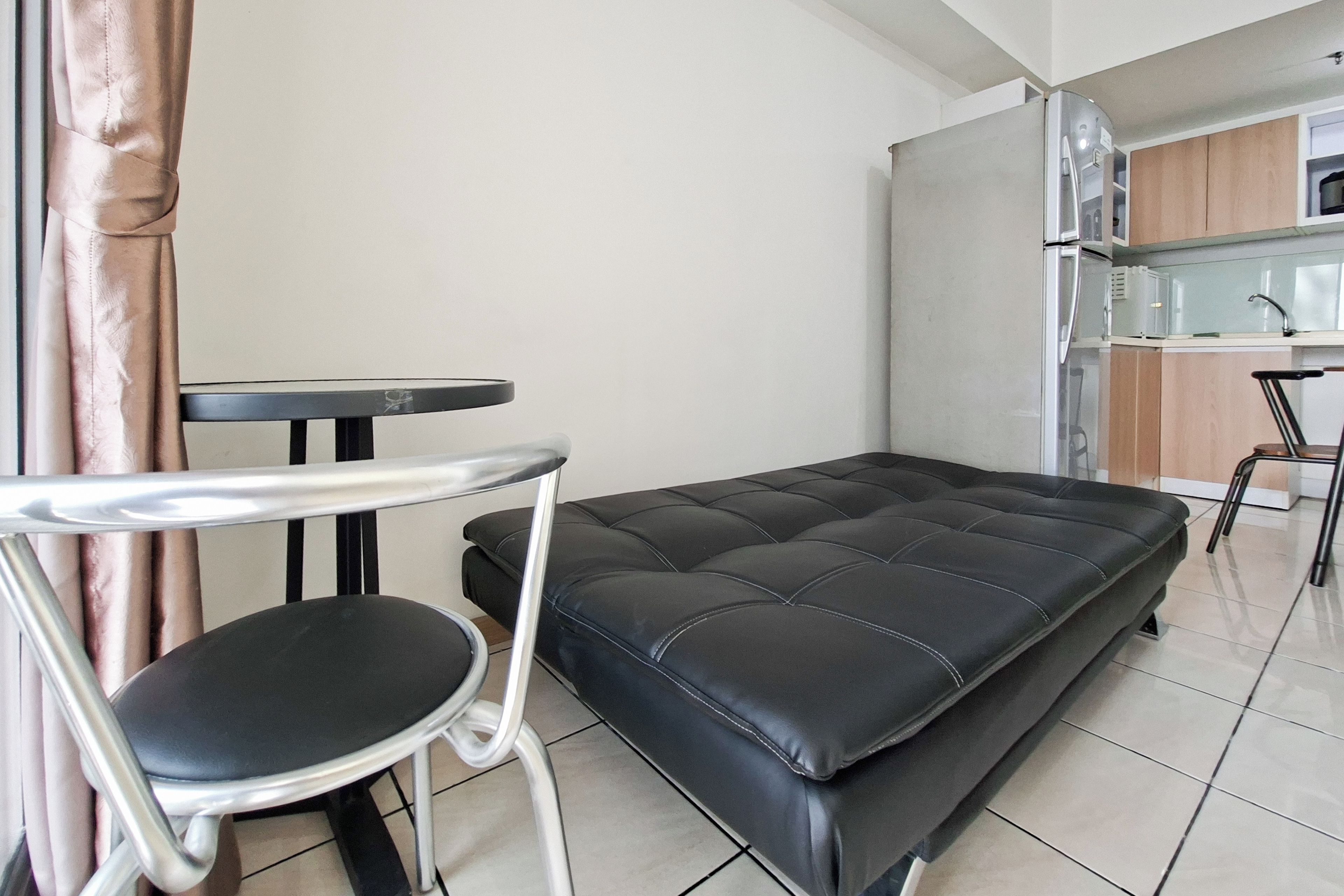 En kompakt opholdsstue med sovesofa, lille rundt bord og en stol.