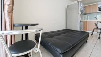 En kompakt opholdsstue med sovesofa, lille rundt bord og en stol.