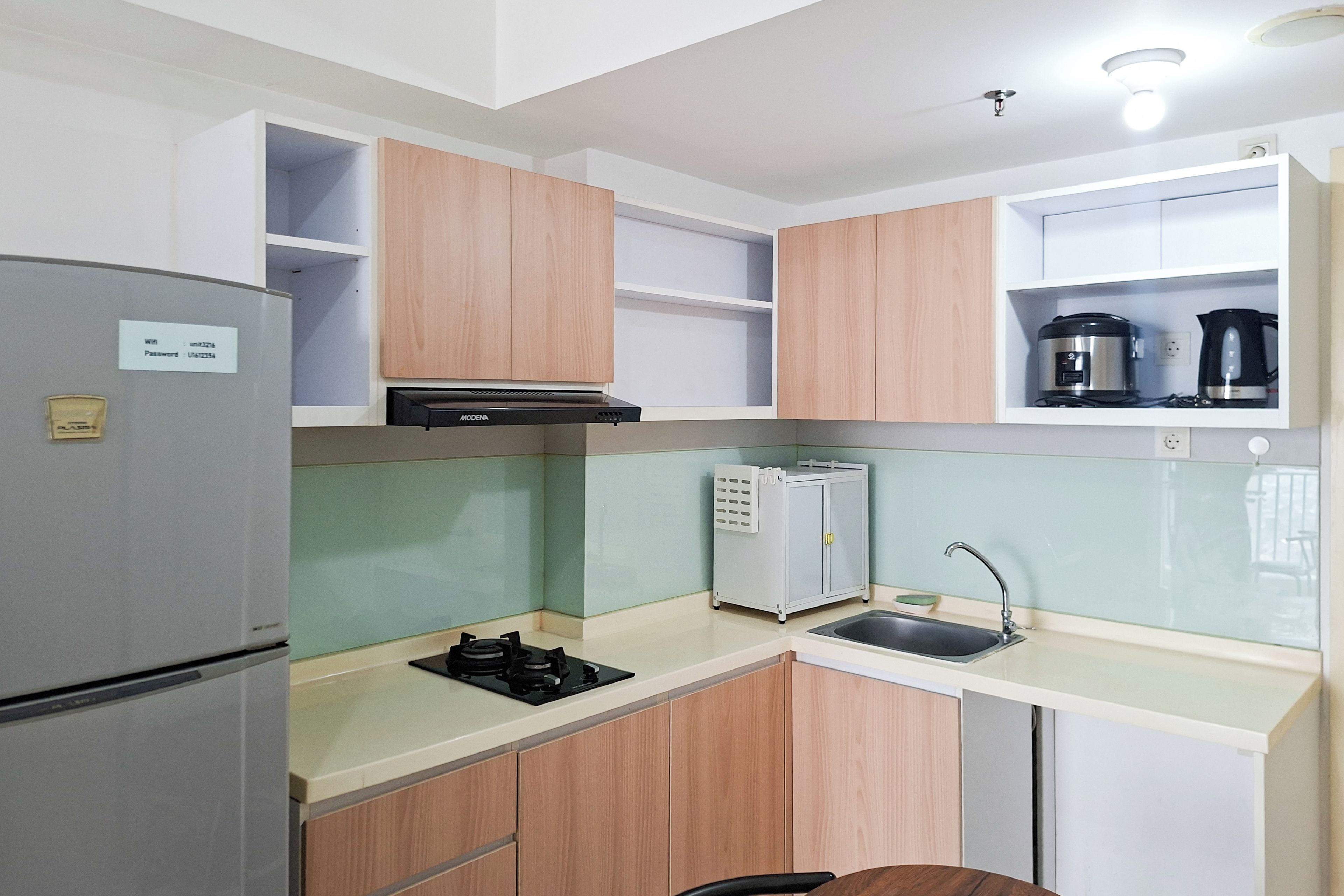 Cocina compacta con refrigerador, estufa, lavabo y cafetera en la encimera.