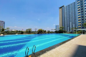 A swimming pool with clear blue water, surrounded by a tiled deck. - Modern Sleek Studio At Apartment Springlake Summarecon Bekasi (Bekasi)