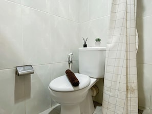 Ein Badezimmer mit Toilette, Duschvorhang und Toilettenpapierhalter.