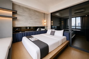 Ein modernes Hotelzimmer mit einem großen Bett, einem Schreibtisch und Blick auf die Stadt durch das Fenster.