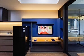 Une cuisine moderne équipée d’un téléviseur encastré, d’un réfrigérateur et d’un plan de travail en bois.