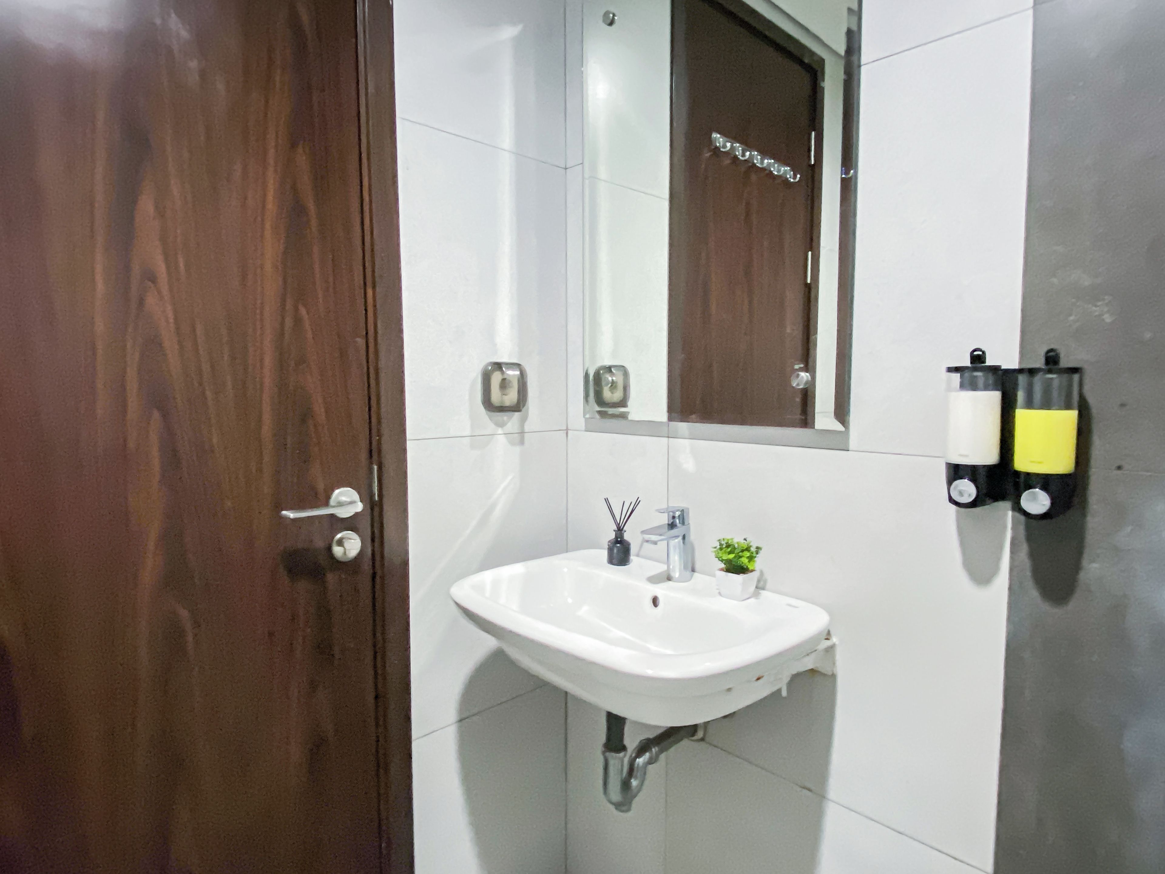 A bathroom with a white sink, a mirror, and a wooden door.