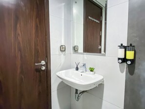 Ein Badezimmer mit einem weißen Waschbecken, einem Spiegel und einer Holztür.