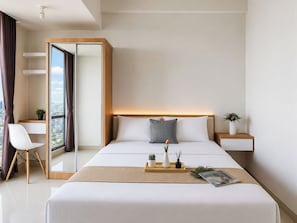 Quarto de hotel moderno com uma cama grande, mesa de cabeceira, cadeira, espelho e vista para a cidade.