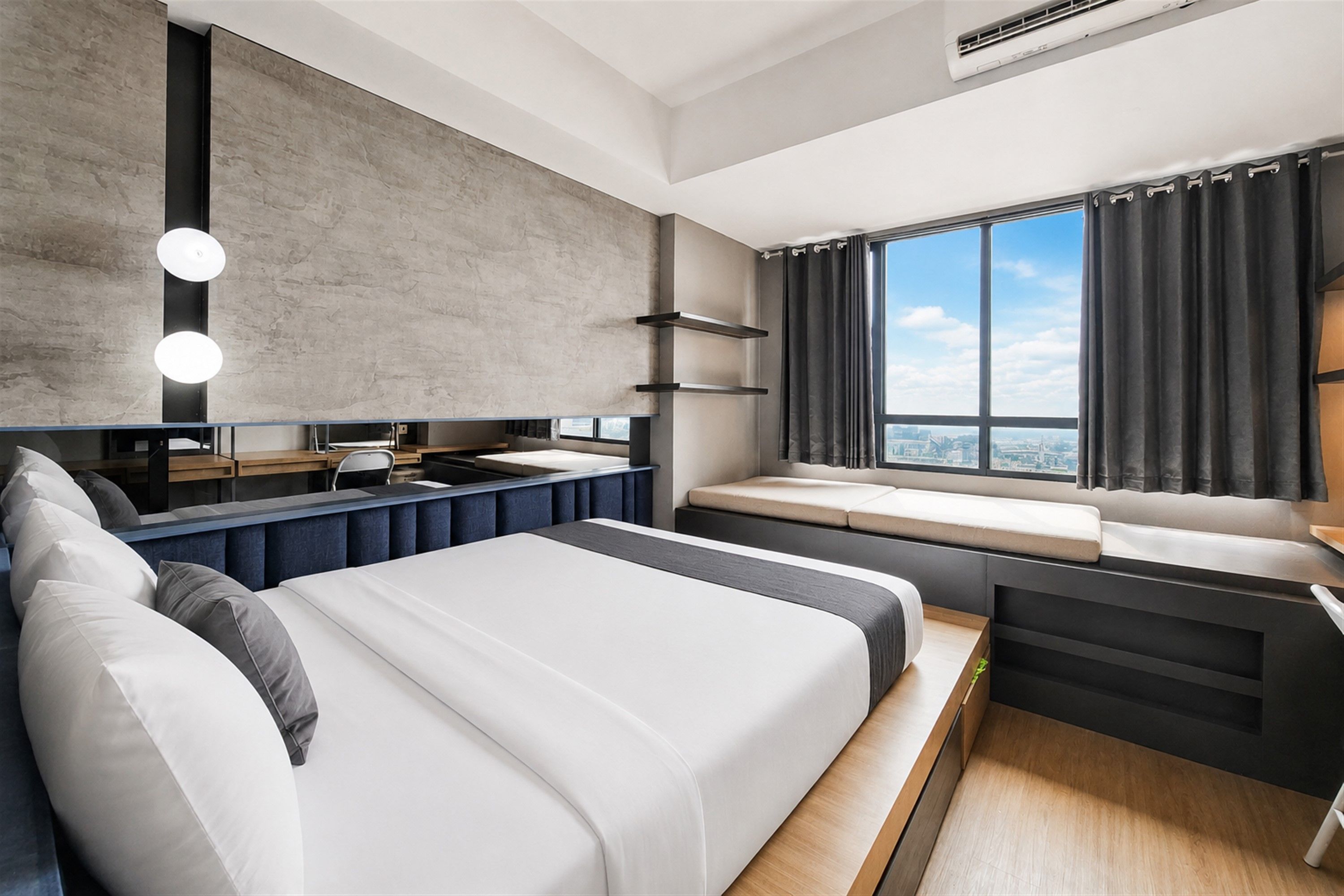 A modern hotel room with a large bed, a desk, and a window with curtains.