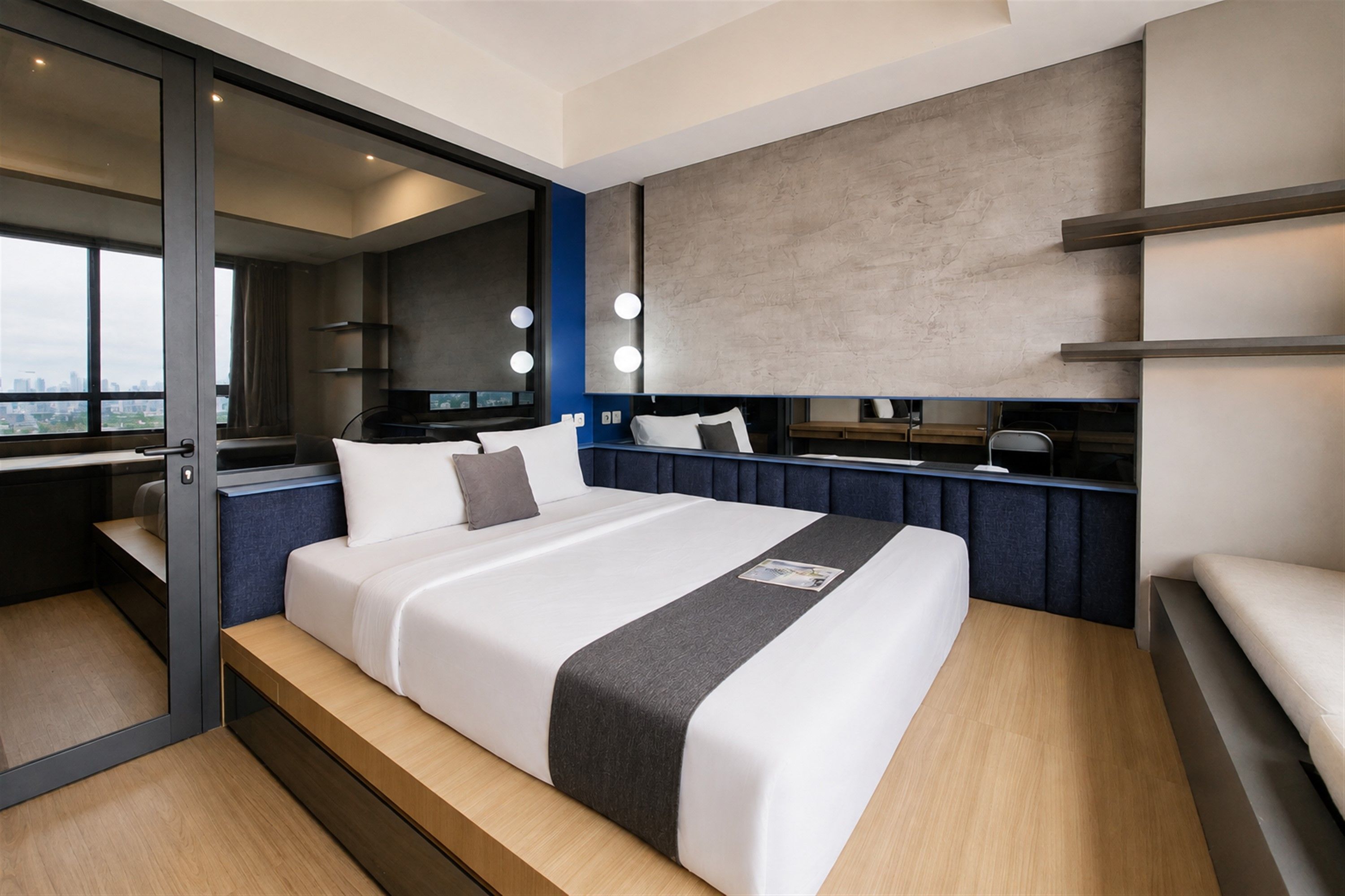 A modern hotel room with a large bed, a desk, and a city view.