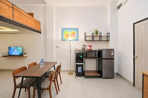 Une cuisine compacte comprenant une table à manger, des chaises, une machine à café, un four à micro-ondes et un réfrigérateur.