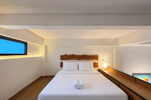 Une chambre d’hôtel avec un lit, une table de chevet, une lampe et une fenêtre.