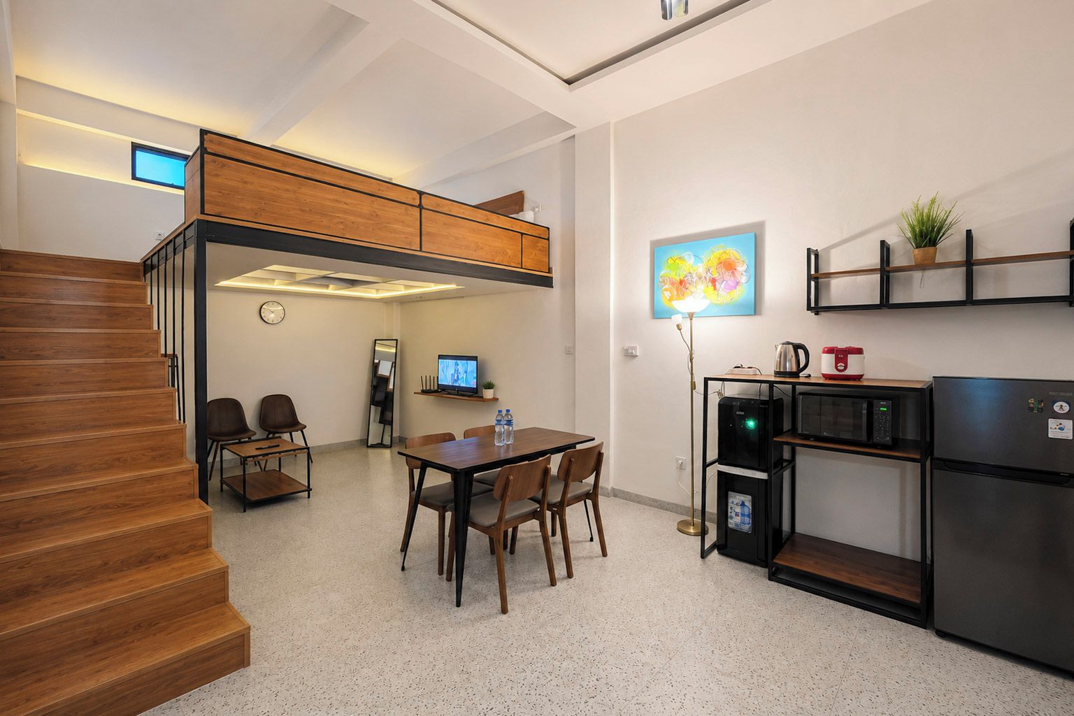 Cozinha compacta com área de refeições, micro-ondas, geladeira e uma mesa pequena com cadeiras.