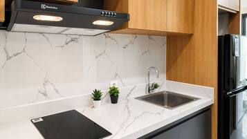 A modern kitchen with a black range hood, a stainless steel sink, and a black induction cooktop.