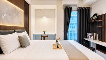 Habitación de hotel con cama, escritorio, ventana con cortinas y aire acondicionado.