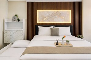 Habitació d'hotel moderna amb un llit gran, una taula de nit, una prestatgeria penjada a la paret i un panell decoratiu de llum.