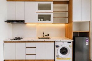 A compact kitchen with a built-in washing machine, a gas stove, and a stainless steel refrigerator. - Bright And Relaxing 1Br At Apartment Lrt City Bekasi (Bekasi)