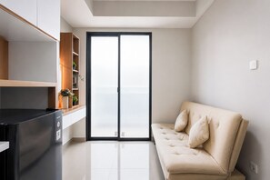 A modern living room with a sofa and a kitchen area with a black countertop. - Bright And Relaxing 1Br At Apartment Lrt City Bekasi (Bekasi)