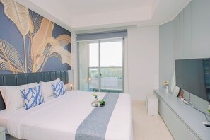 A modern bedroom with a large bed, a flat-screen TV, and a balcony with a view. - Refined And Airy Studio At Apartment Gold Coast (Jakarta)