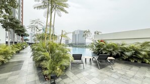 A rooftop terrace with a swimming pool, lounge chairs, and potted plants. - Bright Elegant Studio At Apartment Antasari Place (Jakarta)