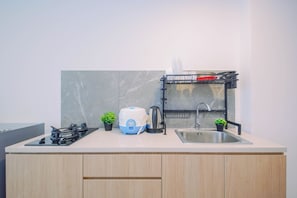Cozinha moderna com lava-louças embutida, chaleira e pia.