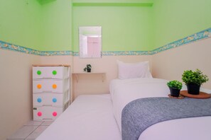Een kamer met een bed, een dressoir met lades, een spiegel en twee potplanten.