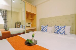 Ein Hotelzimmer mit Bett, Schreibtisch, Spiegel und Kleiderschrank.