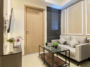 Ein modernes Wohnzimmer mit einem Glastisch, einer Couch, einer Tür und einem Fenster mit Jalousien.